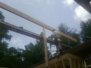 Carpenter setting a ridge beam over a new addition frame — Ice Dam Removal by Roofing Brothers in Giddings