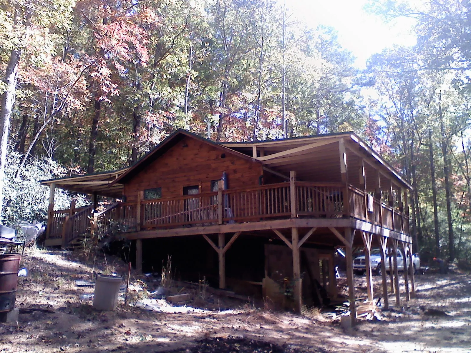 Log cabin with a wraparound porch and metal roof in the fall in Giddings