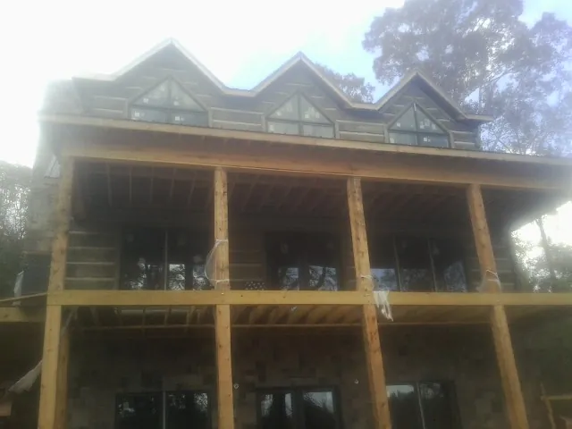 Dormers and porch framing on a large log home under construction — Roof Coating work by our crew in Giddings