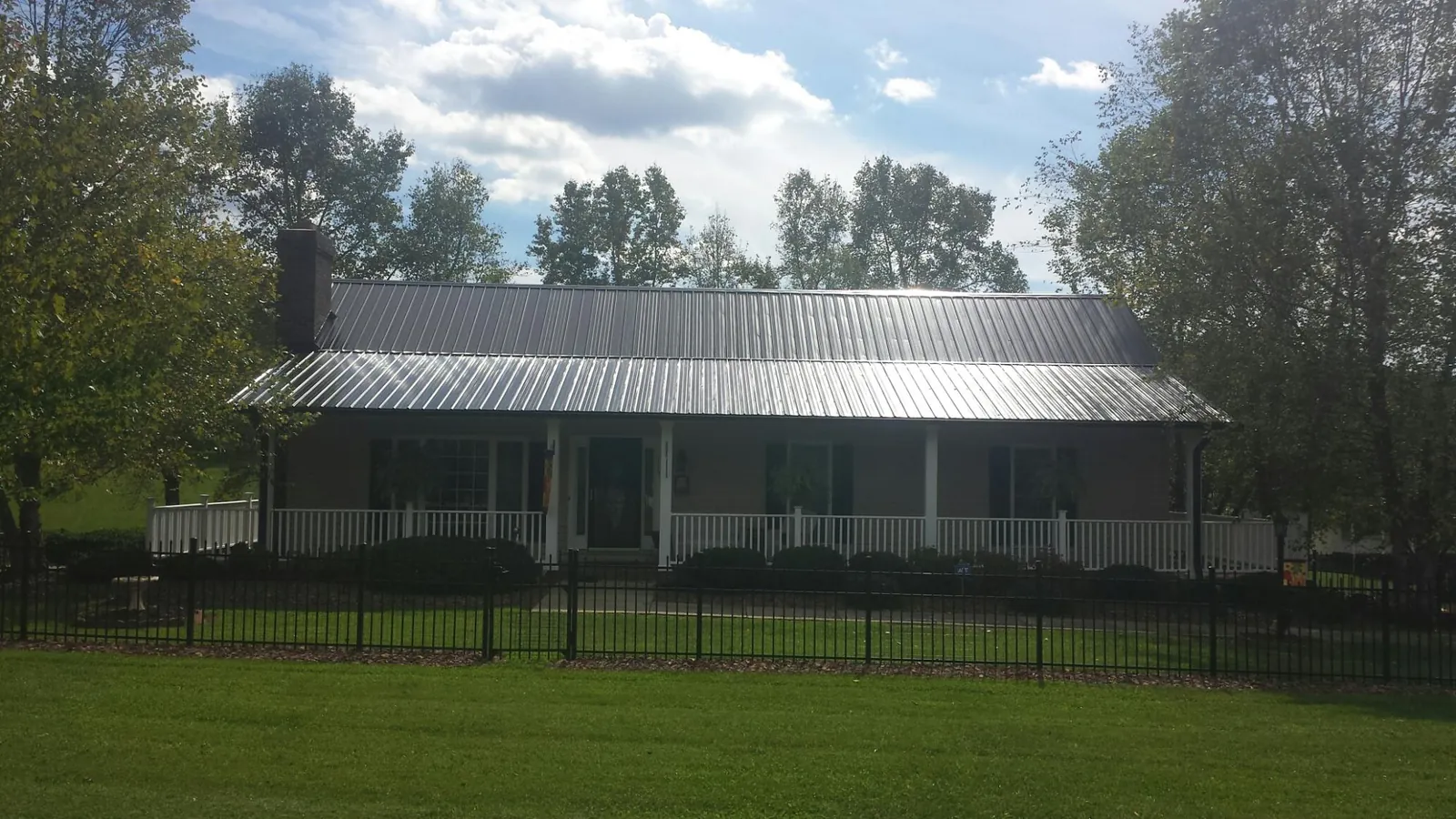 Gray metal roof on a brick ranch with a full width front porch — Gutter Guard Installation work by our crew in Giddings