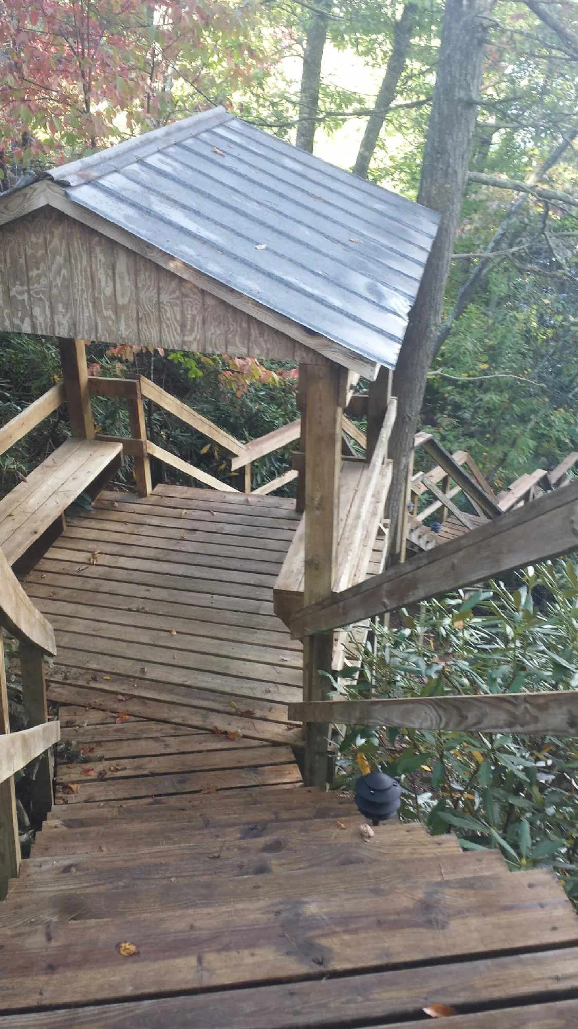 Metal roofed shelter over wooden steps on a wooded walkway — Skylight Repair & Installation work by our crew in Giddings