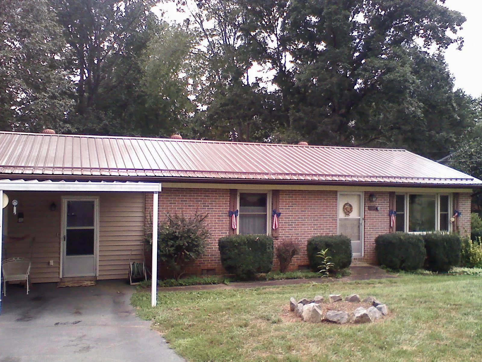 Bronze metal roof and carport on a brick ranch home — Roof Repair work by our crew in Giddings