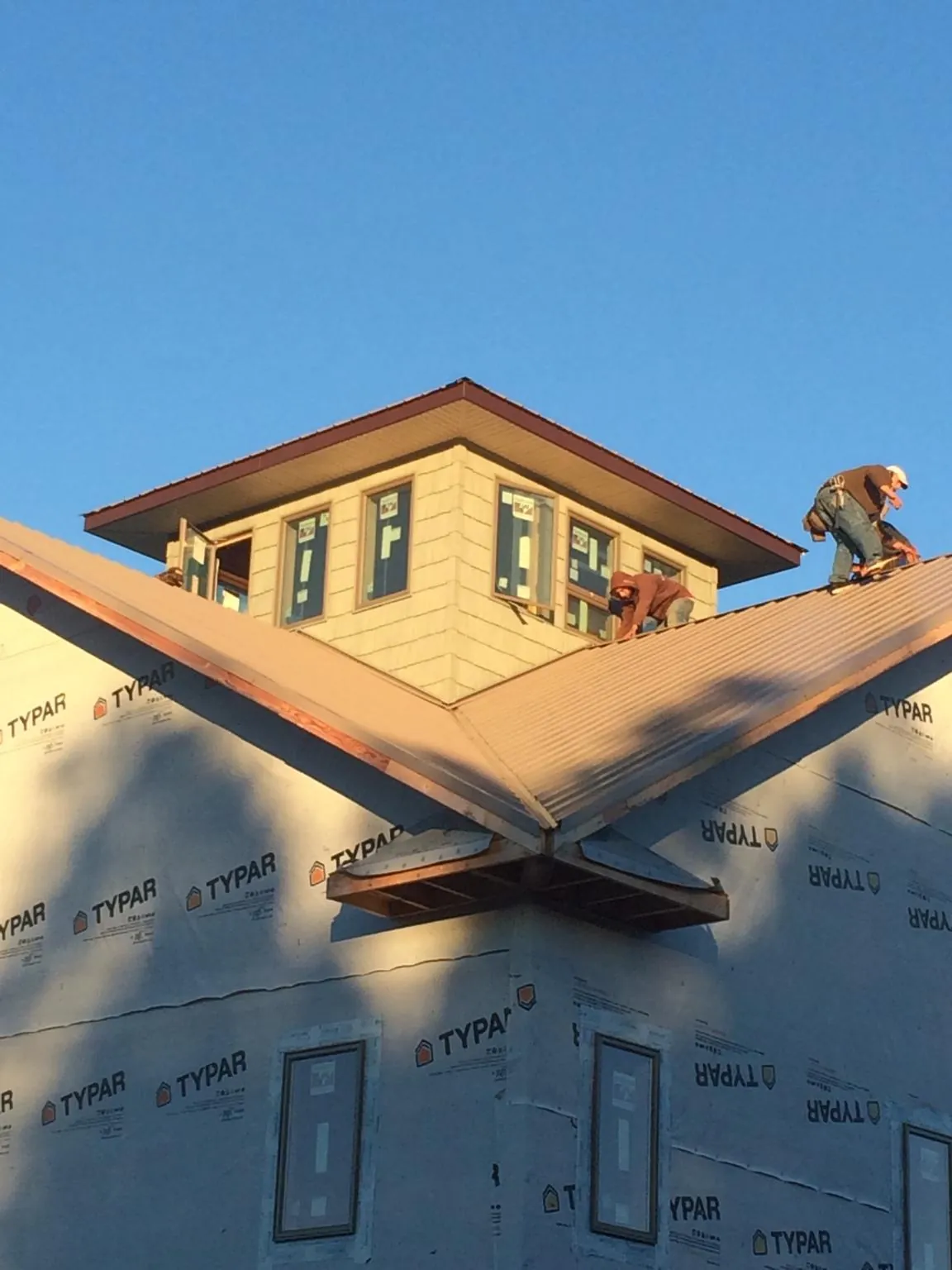 Roofers working around a rooftop cupola on a new metal roof at sunset — Roof Waterproofing in Giddings by Roofing Brothers